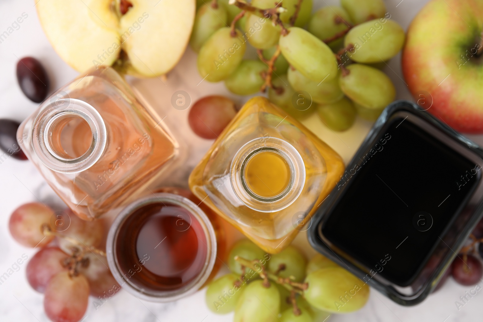 Photo of Different types of vinegar and ingredients on light marble table, flat lay