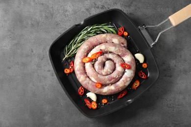 Pan with raw homemade sausage, chili pepper, garlic and rosemary on grey table, top view