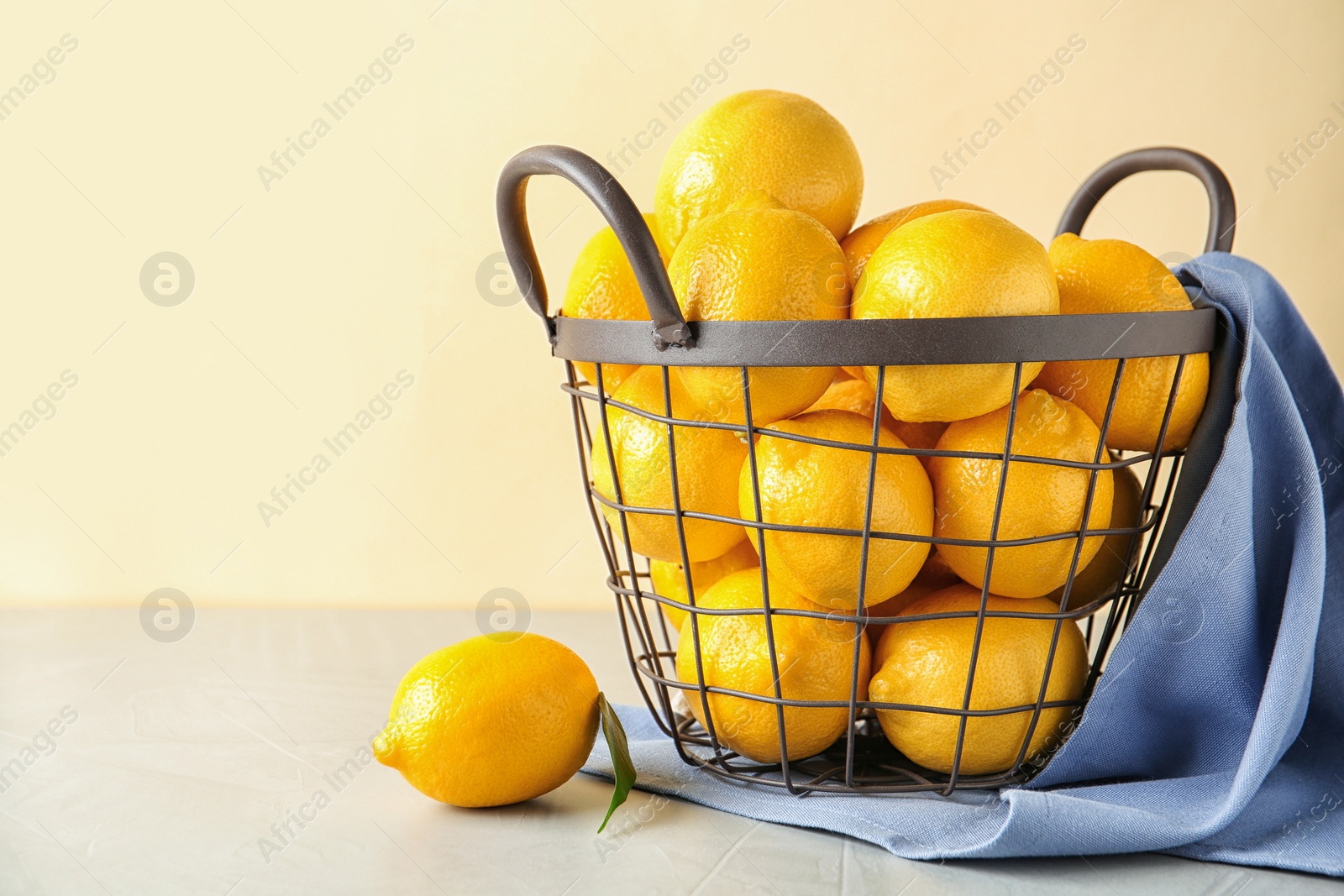 Photo of Metal basket with fresh ripe lemons on table