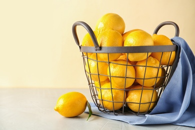 Photo of Metal basket with fresh ripe lemons on table