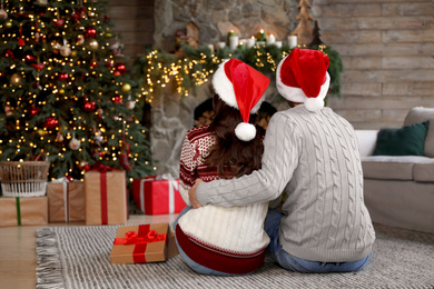 Photo of Happy young couple wearing Santa hats in living room decorated for Christmas