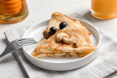 Thin pancakes with berries and nuts on plate, closeup