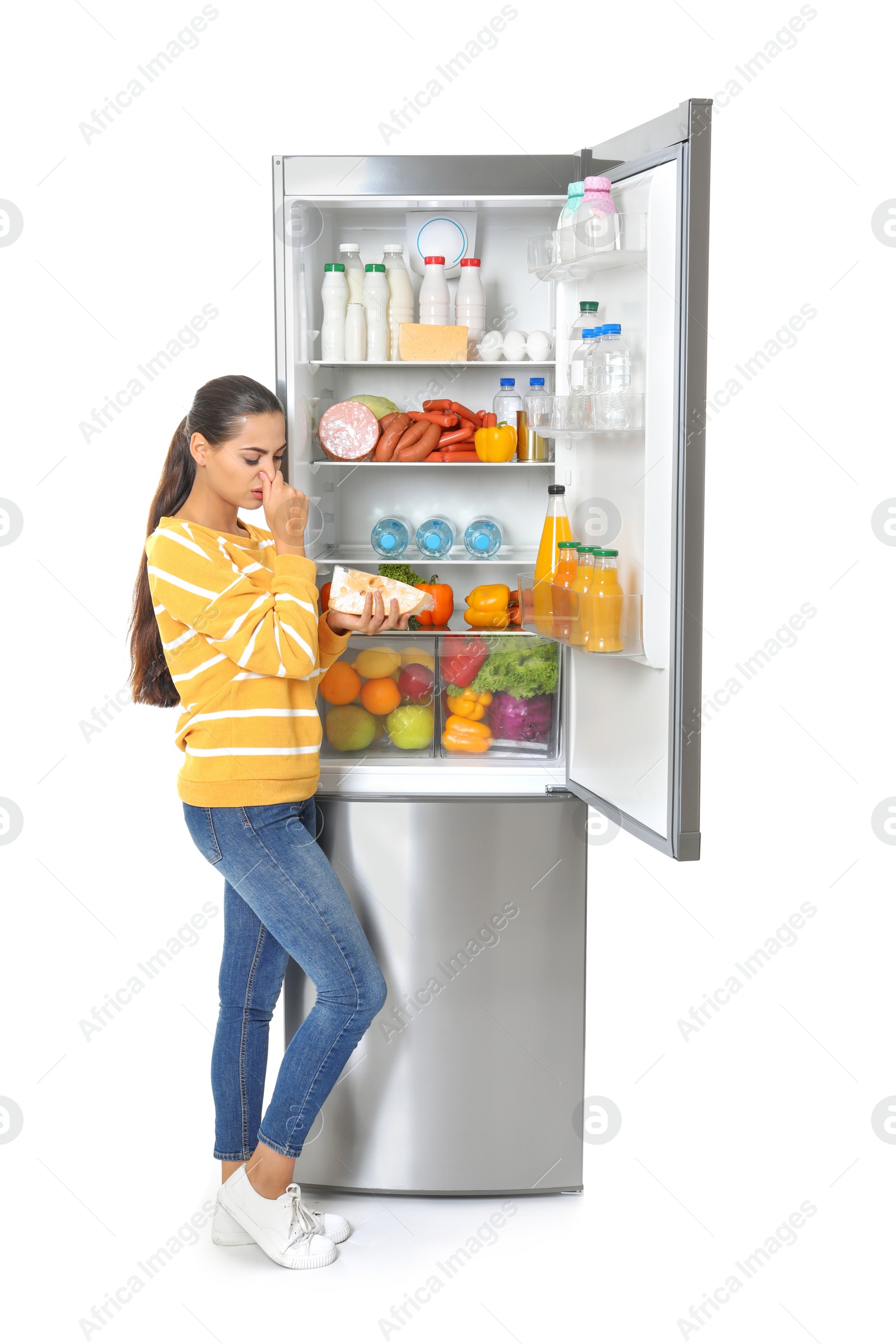 Photo of Young woman with expired cheese near open refrigerator on white background