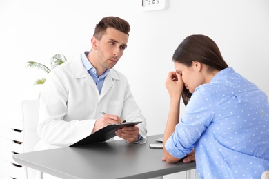 Photo of Depressed young woman having appointment with psychologist in office