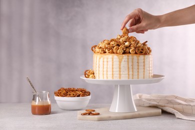 Photo of Woman decorating caramel drip cake at light table, closeup. Space for text
