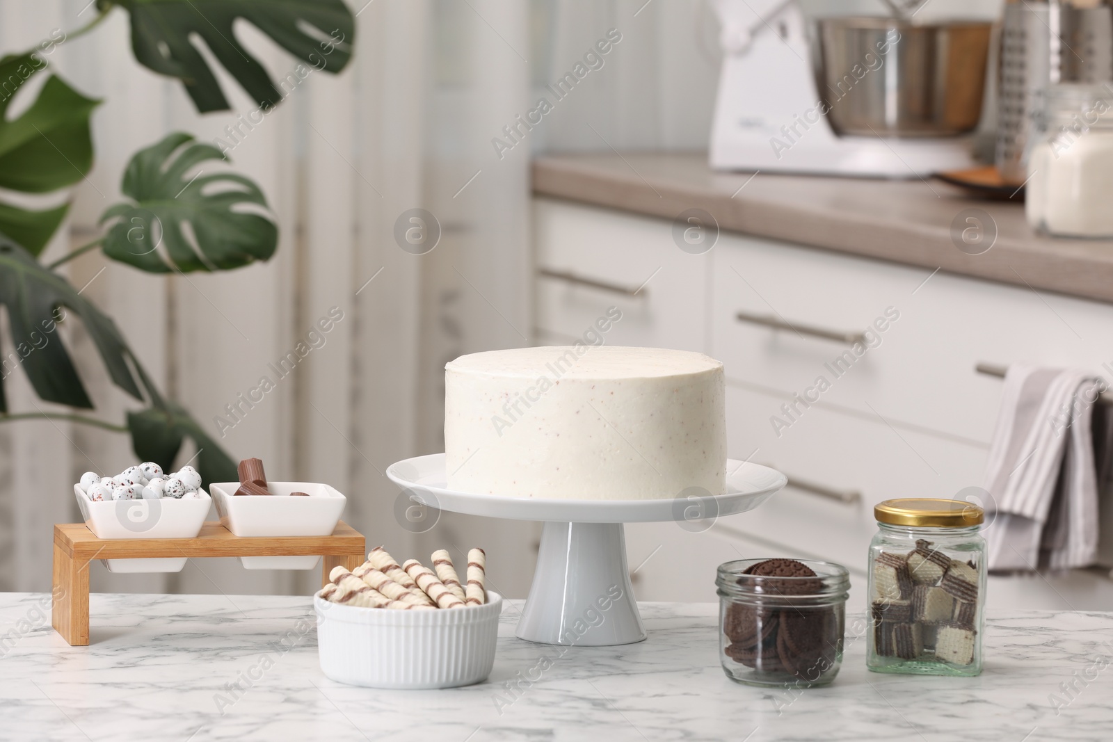 Photo of Delicious cake and sweets for decoration on white marble table in kitchen