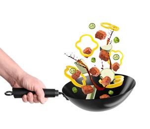 Man tossing ingredients in wok on white background, closeup