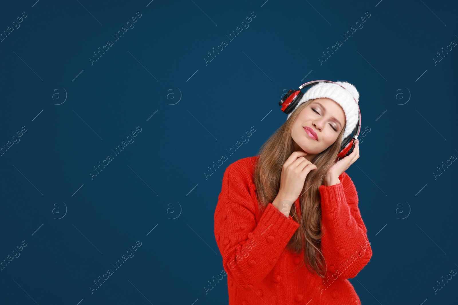 Photo of Young woman listening to music with headphones on dark blue background, space for text