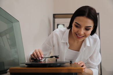 Happy young woman using turntable at home