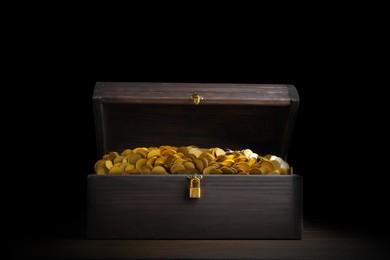 Open treasure chest with gold coins on wooden table