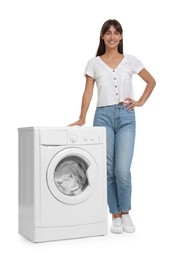 Beautiful woman near washing machine with laundry on white background