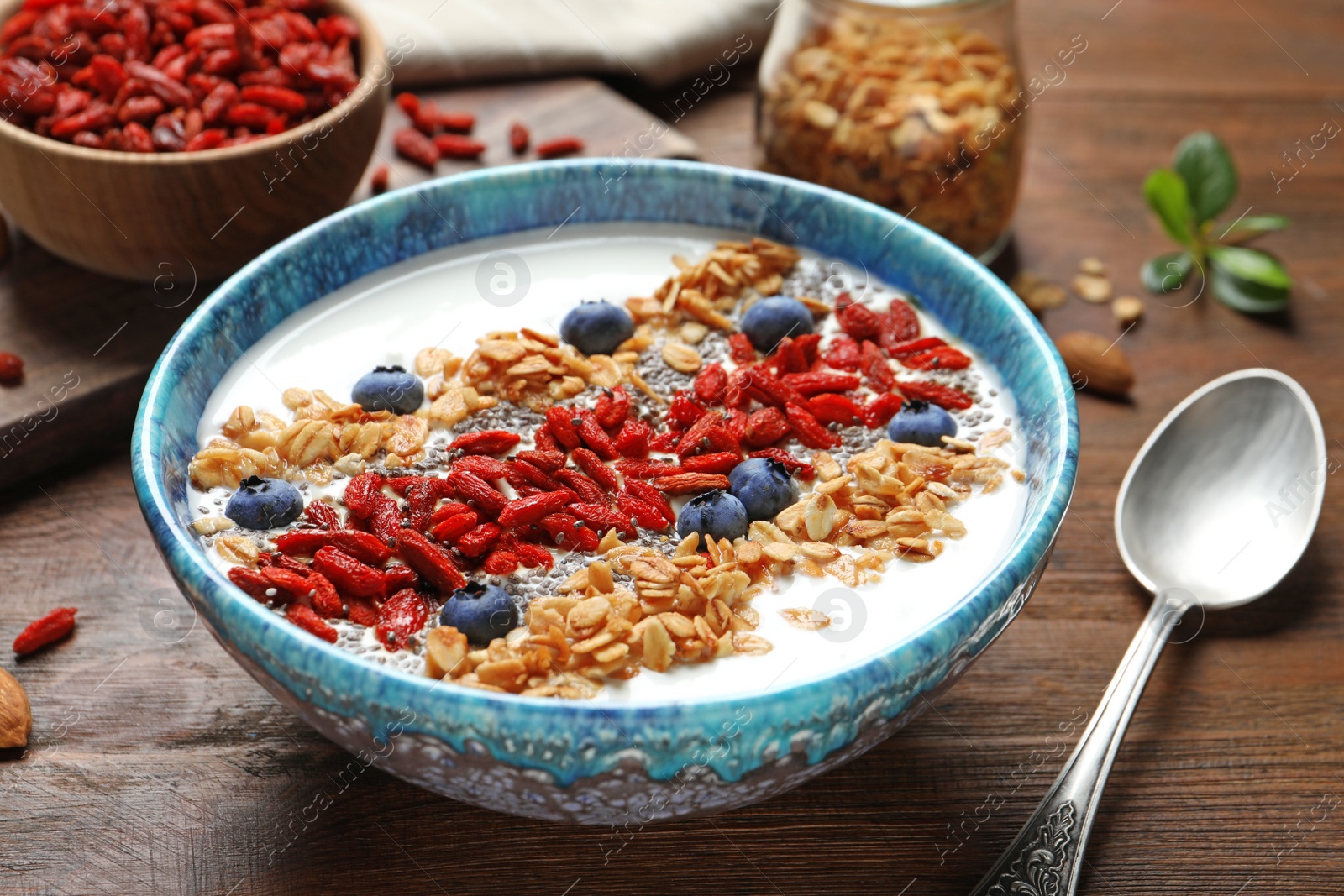 Photo of Smoothie bowl with goji berries and spoon on wooden table