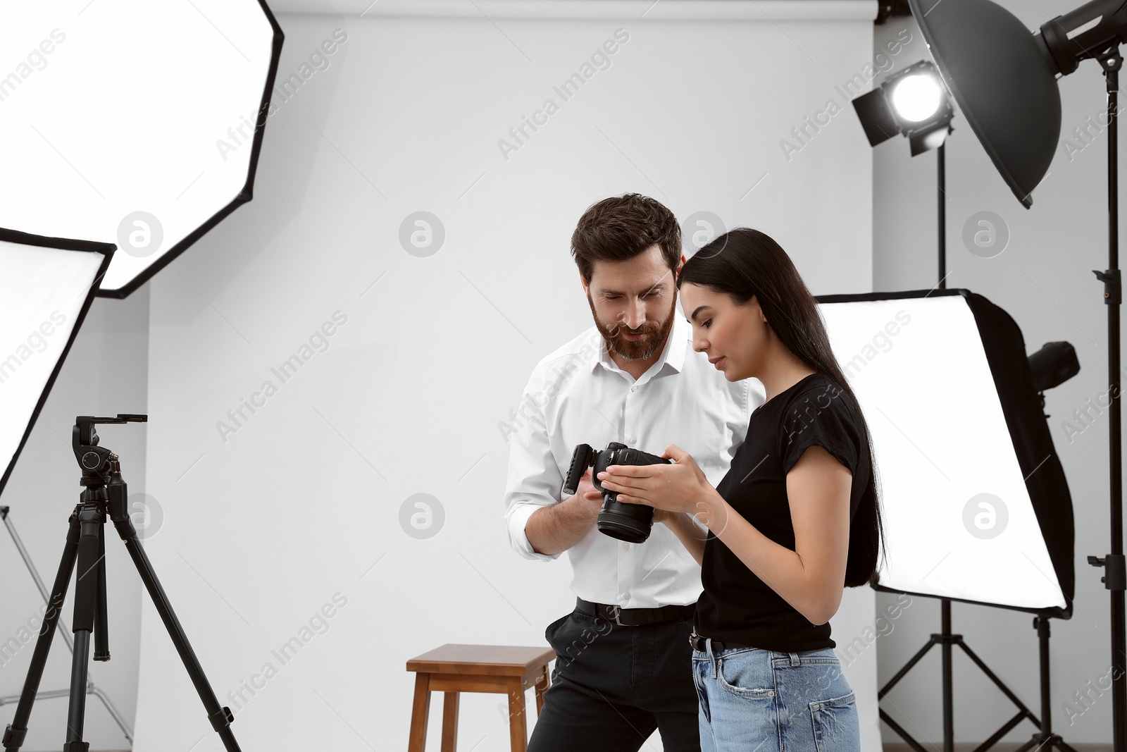 Photo of Professional photographer and model looking at pictures on camera in modern studio