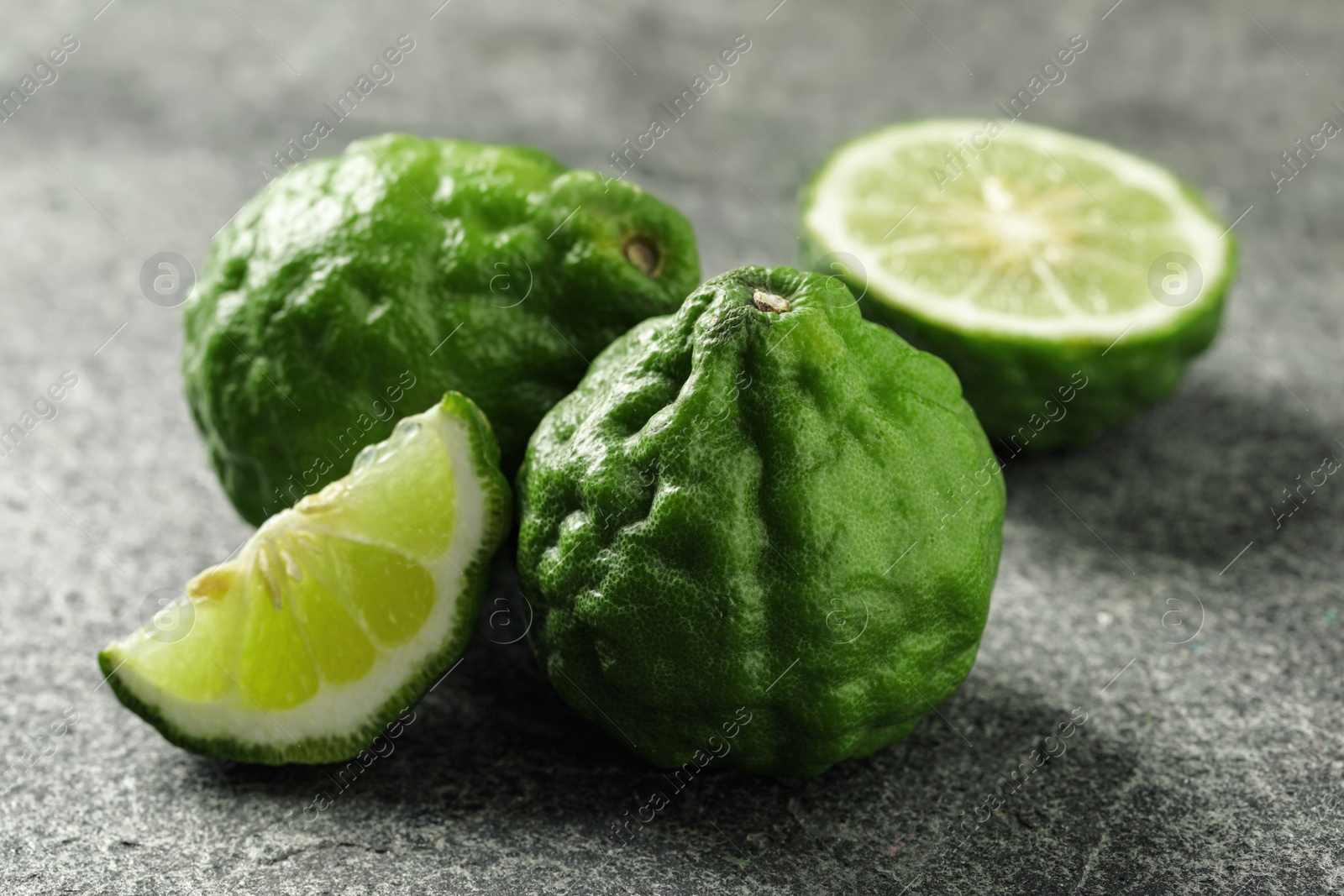 Photo of Whole and cut ripe bergamot fruits on grey table