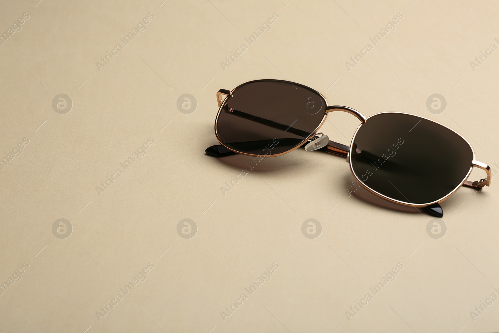 Photo of Stylish sunglasses on beige background, space for text. Fashionable accessory