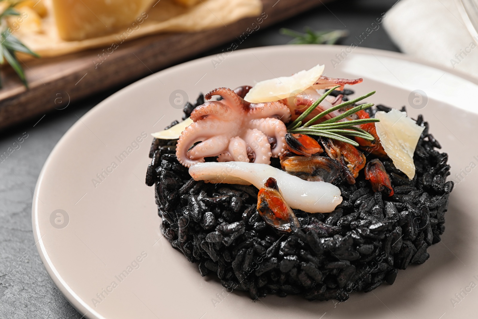 Photo of Delicious black risotto with seafood on grey table, closeup