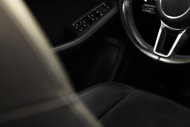 Steering wheel and leather seat inside of modern car, closeup