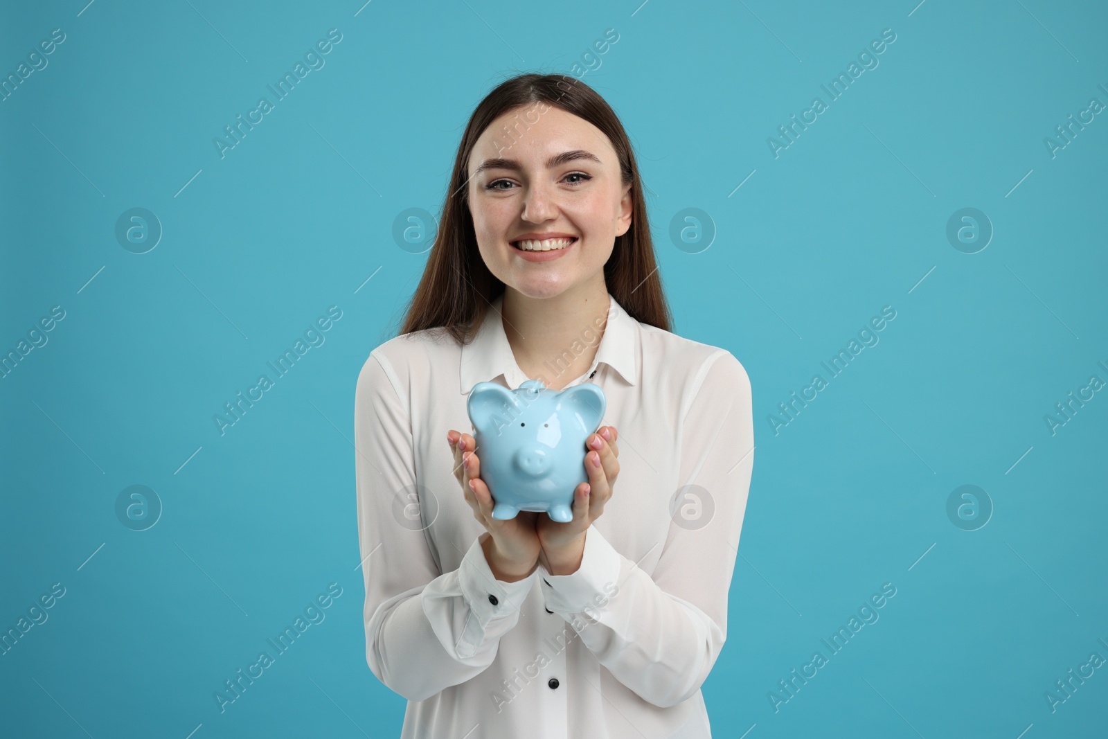 Photo of Happy woman with piggy bank on light blue background