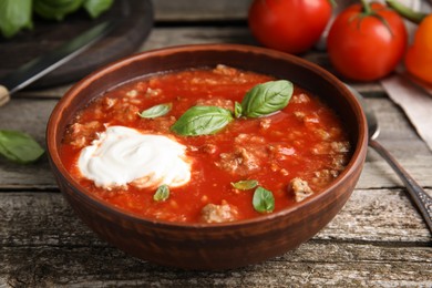 Photo of Bowl of delicious stuffed pepper soup on wooden table, closeup