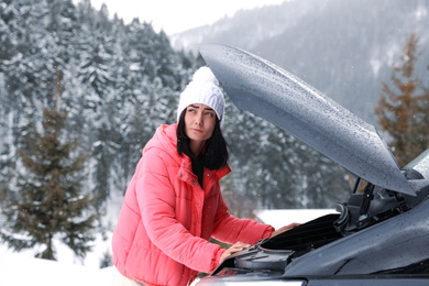 Photo of Stressed woman near broken car outdoors on winter day