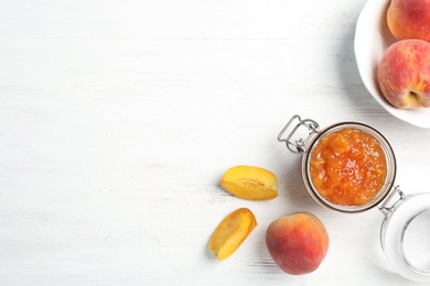 Flat lay composition with jar of tasty peach jam and fresh fruit on wooden table