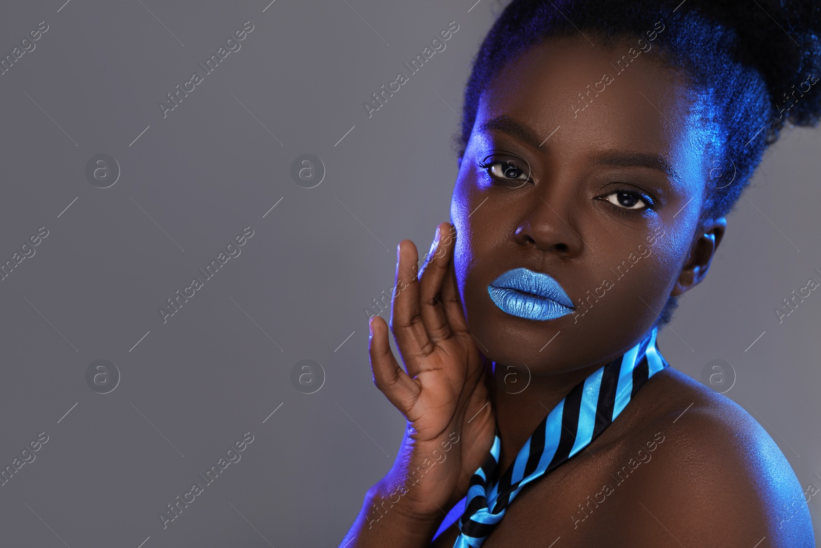 Photo of Fashionable portrait of beautiful woman with bright makeup on grey background, space for text