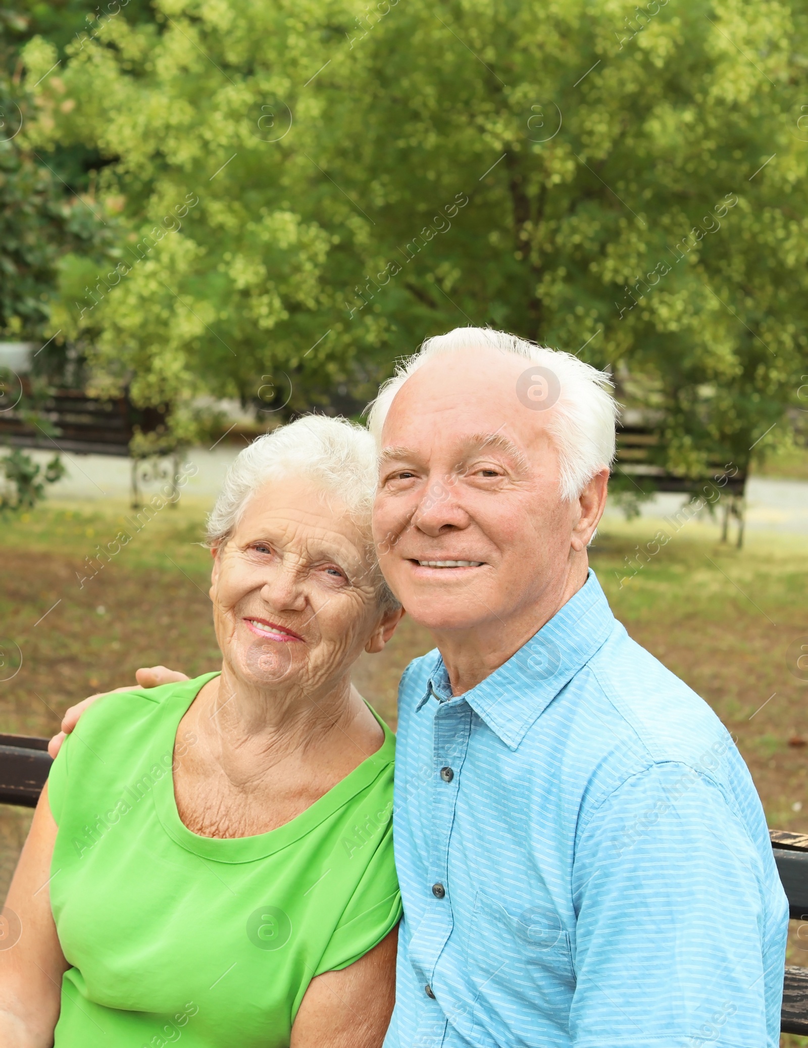 Photo of Elderly couple resting on bench in park