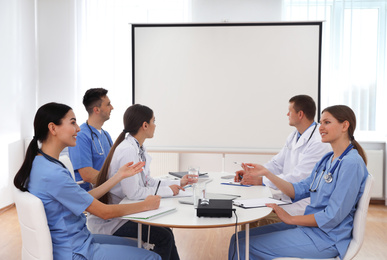 Photo of Team of doctors using video projector during conference indoors