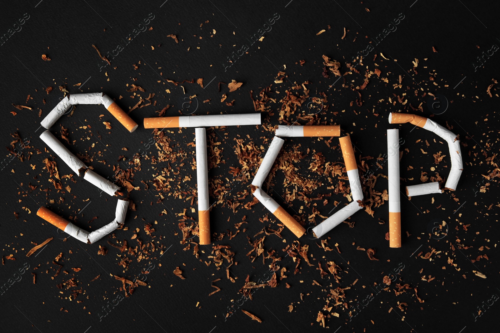 Photo of Word Stop made of broken cigarettes on black background, flat lay. Quitting smoking concept