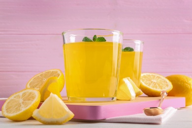 Glasses of lemon jelly served on light wooden table against color background