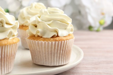 Photo of Tasty cupcakes with vanilla cream on pink wooden table, closeup. Space for text