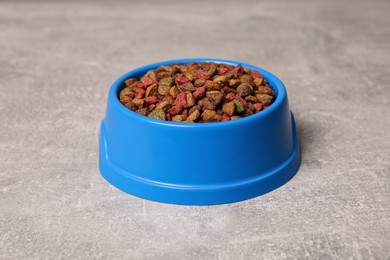 Photo of Dry food in blue pet bowl on grey surface