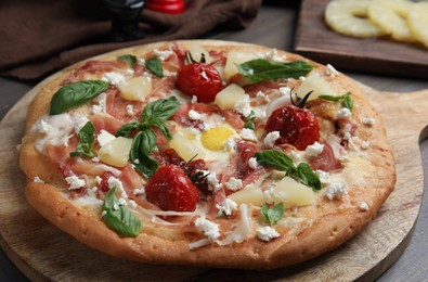 Photo of Pita pizza with prosciutto, pineapple, grilled tomatoes and egg on wooden table, closeup