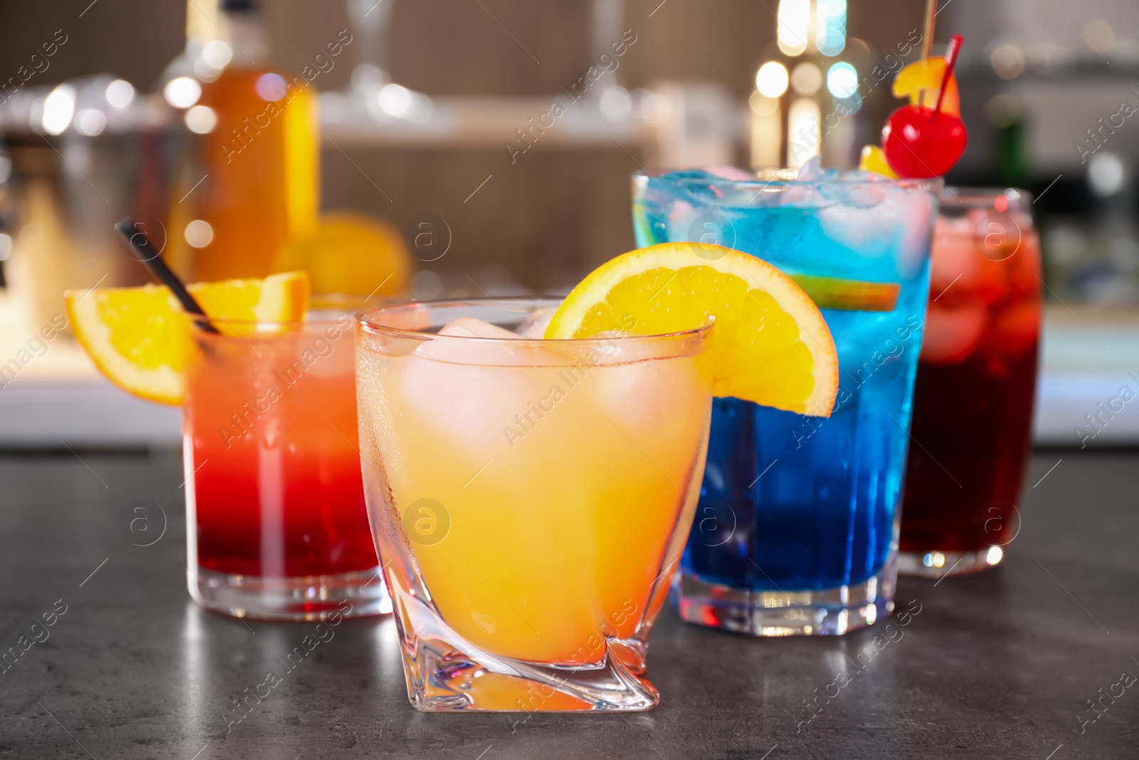 Photo of Different delicious cocktails on grey table in bar