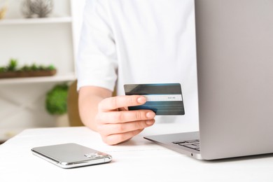 Photo of Online payment. Woman with laptop, smartphone and credit card at white table, closeup