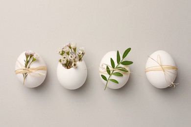Photo of Festive composition with chicken eggs and natural decor on light grey background, flat lay. Happy Easter