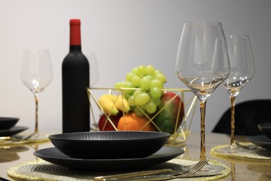 Photo of Bottle of wine, plates, fresh fruits and glasses on table
