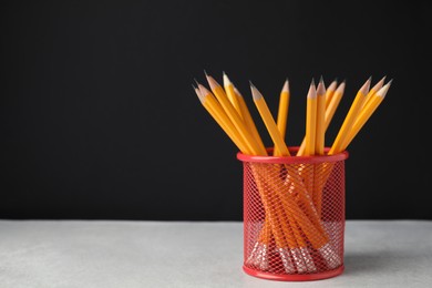 Photo of Many sharp pencils in holder on light table against black background, space for text