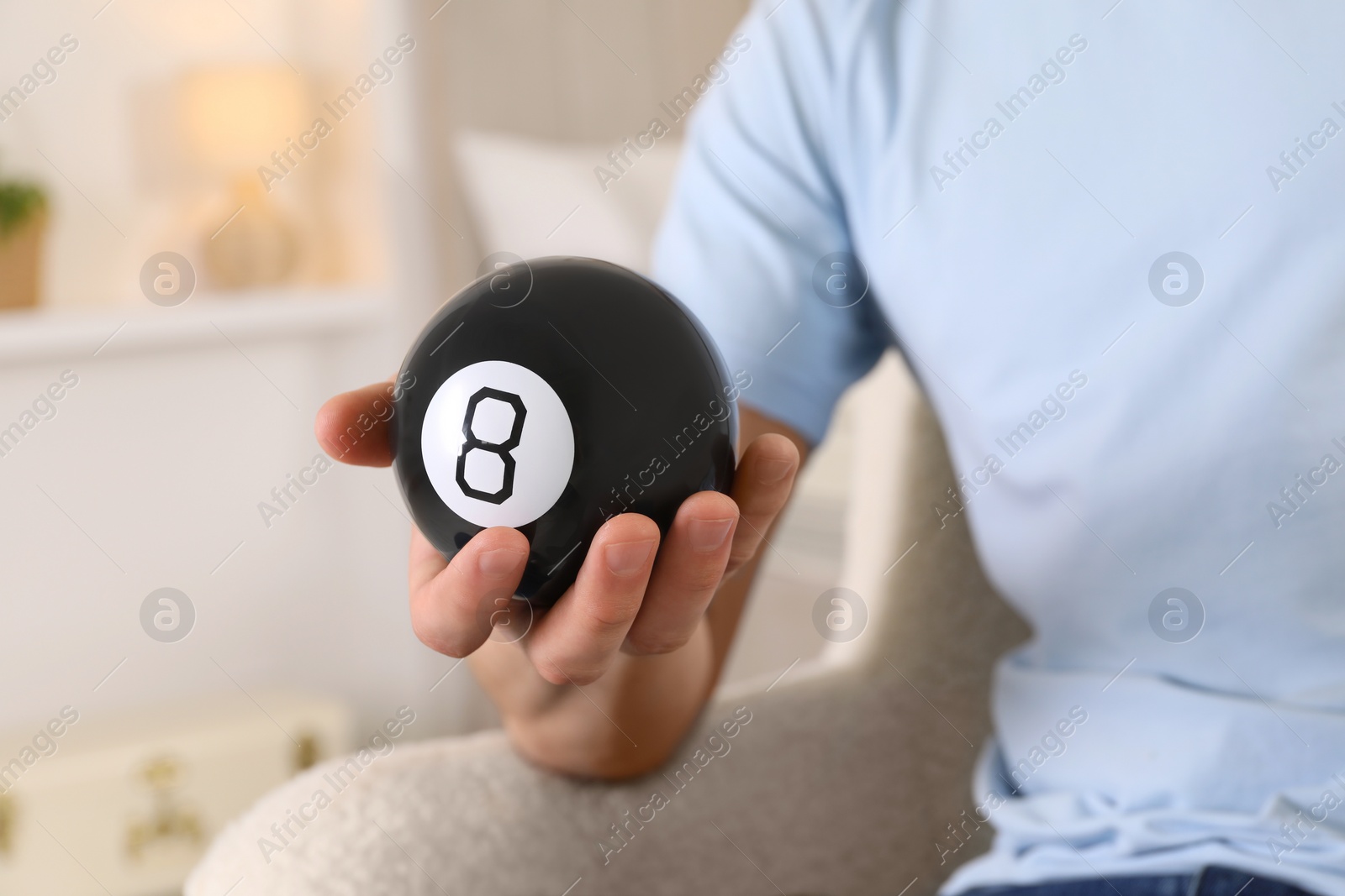 Photo of Man holding magic eight ball indoors, closeup