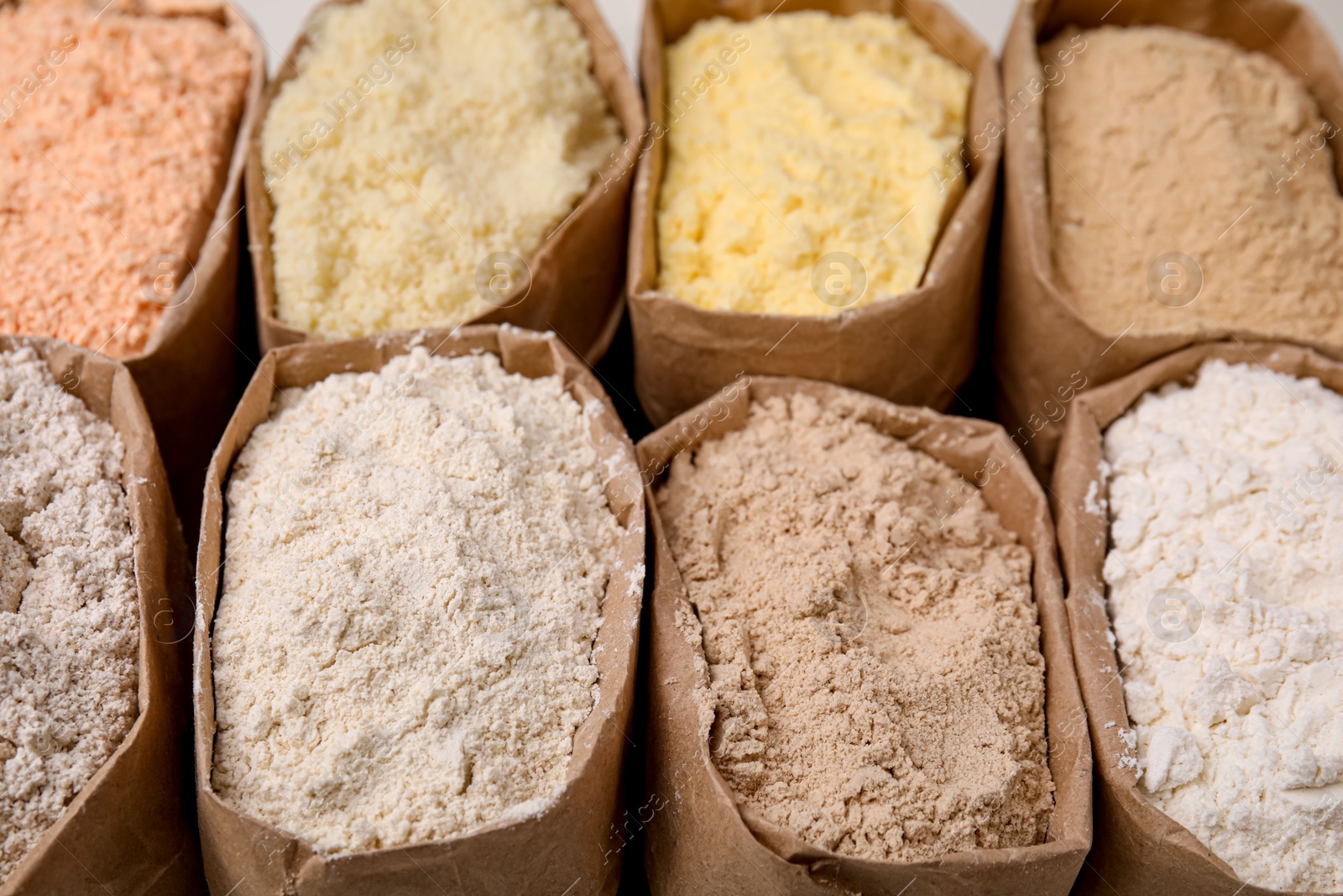 Photo of Paper sacks with different types of flour as background, closeup