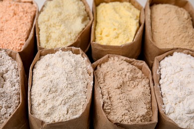 Paper sacks with different types of flour as background, closeup