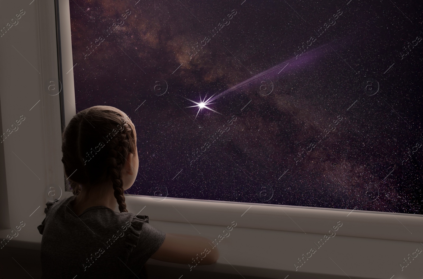 Image of Little girl near window looking at shooting star in beautiful night sky