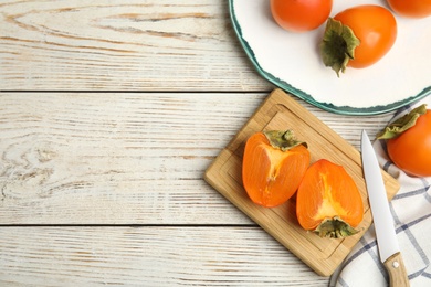 Photo of Tasty ripe persimmons on white wooden table, flat lay. Space for text
