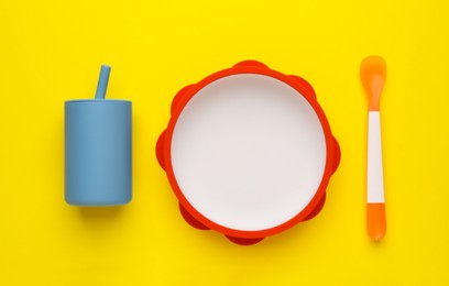 Photo of Set of plastic dishware on yellow background, flat lay. Serving baby food