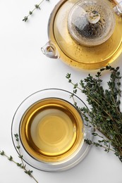 Aromatic herbal tea with thyme on white table, flat lay