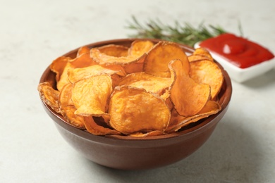 Delicious sweet potato chips in bowl on table