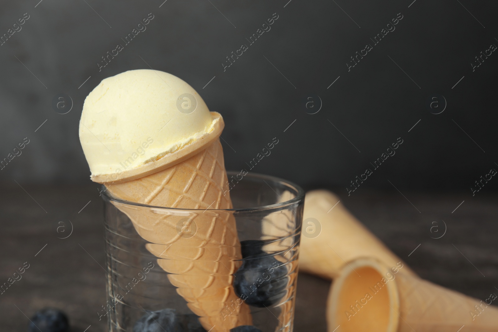 Photo of Delicious vanilla ice cream in waffle cone served on table, closeup. Space for text