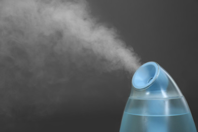 Photo of Modern air humidifier on grey background, closeup. Space for text