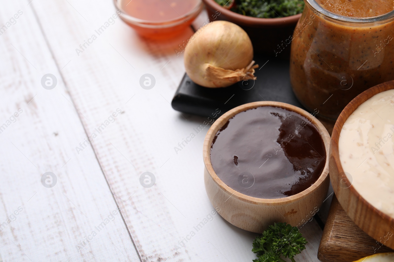 Photo of Fresh marinades and ingredients on white wooden table, space for text