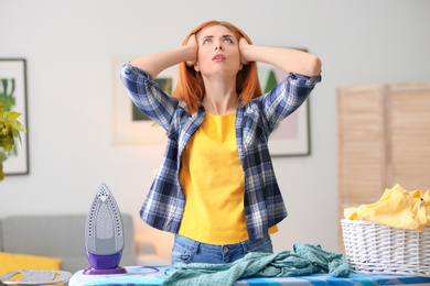 Photo of Tired housewife ironing clothes at home